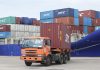 An orange truck offloads shipping containers at Sihanoukville Autonomous Port in Cambodia