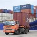 An orange truck offloads shipping containers at Sihanoukville Autonomous Port in Cambodia