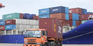 An orange truck offloads shipping containers at Sihanoukville Autonomous Port in Cambodia