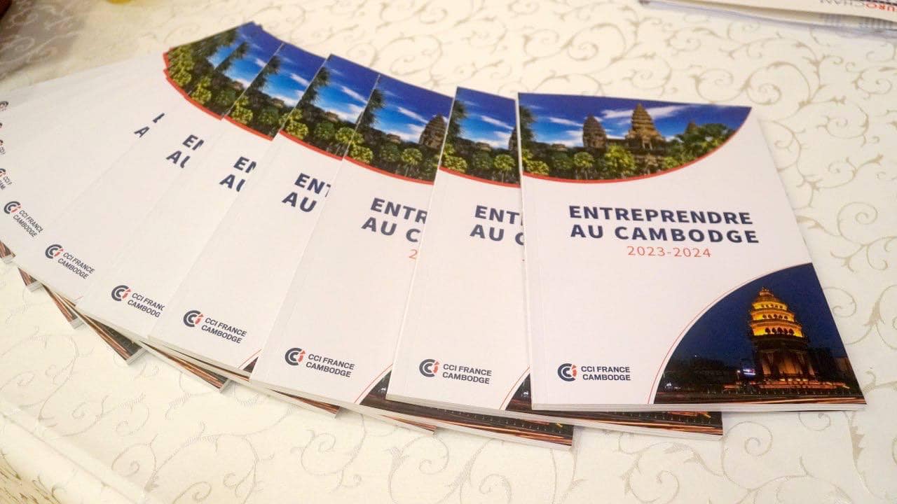 Several 'Doing Business in Cambodia' guides by CCIFC for the year 2023-2024, are splayed out on a table